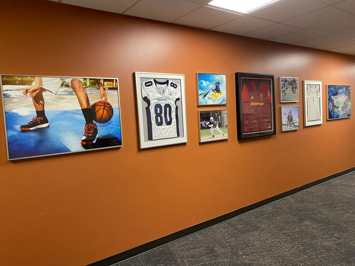 A hallway wall featuring a gallery of framed sports memorabilia, jerseys, and action photography.