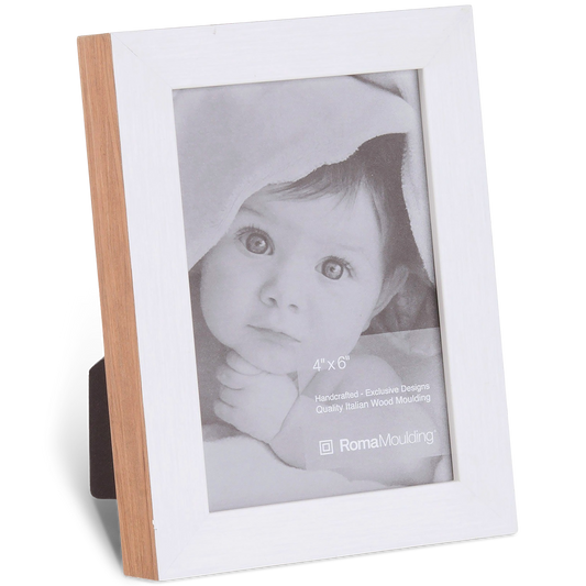 Framed photo of a baby wrapped in a soft blanket, gazing upward. The frame is wood with a white border, displaying a gentle and serene expression.