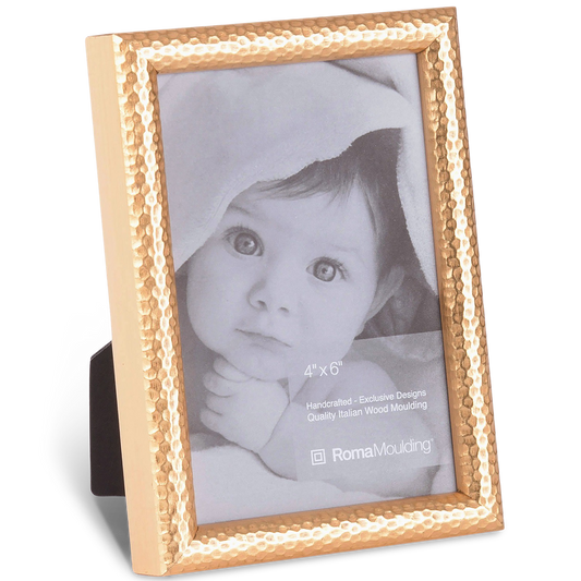 A bronze-colored, textured photo frame stands upright, displaying a black-and-white photo of an infant wrapped in a soft blanket, exuding warmth and innocence.