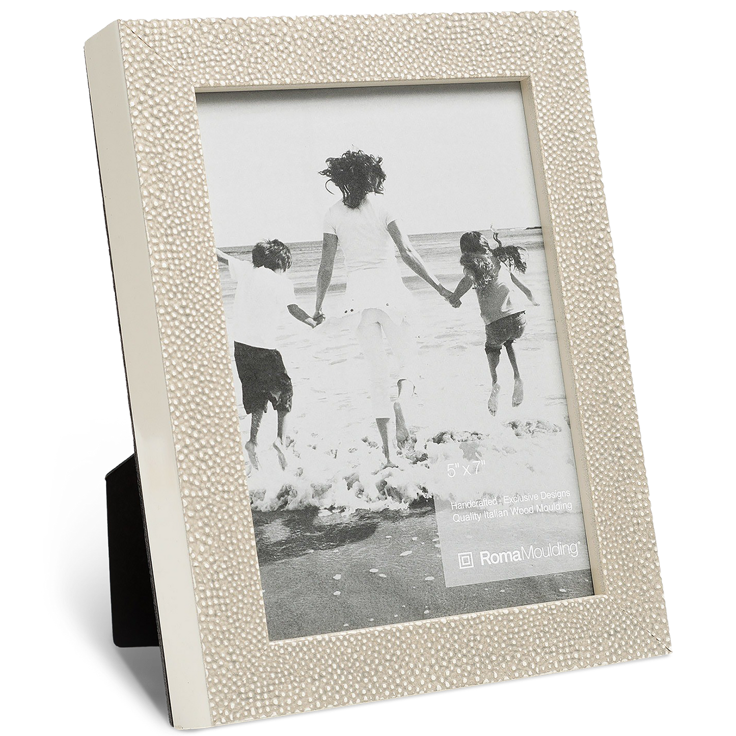 Beige picture frame with a textured border holds a black-and-white photo of three people joyfully running towards the ocean waves, conveying happiness.