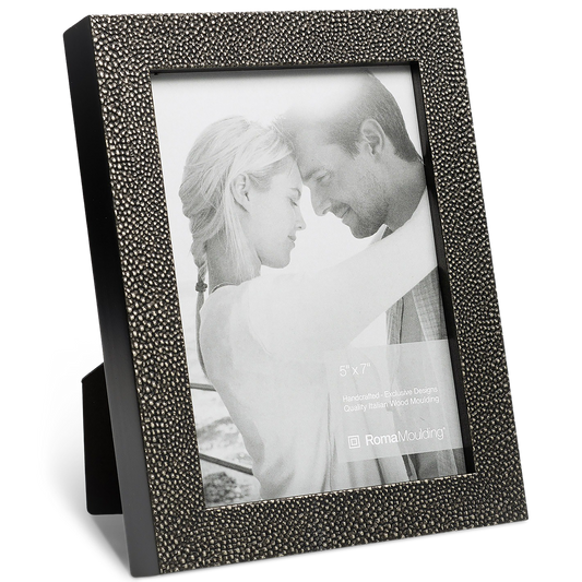 A textured dark grey picture frame holds a black-and-white photo of a couple gently embracing, conveying warmth and affection. The frame stands upright.