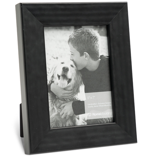 A black frame holds a black-and-white photo of a young boy affectionately hugging a smiling golden retriever. The scene conveys warmth and friendship.