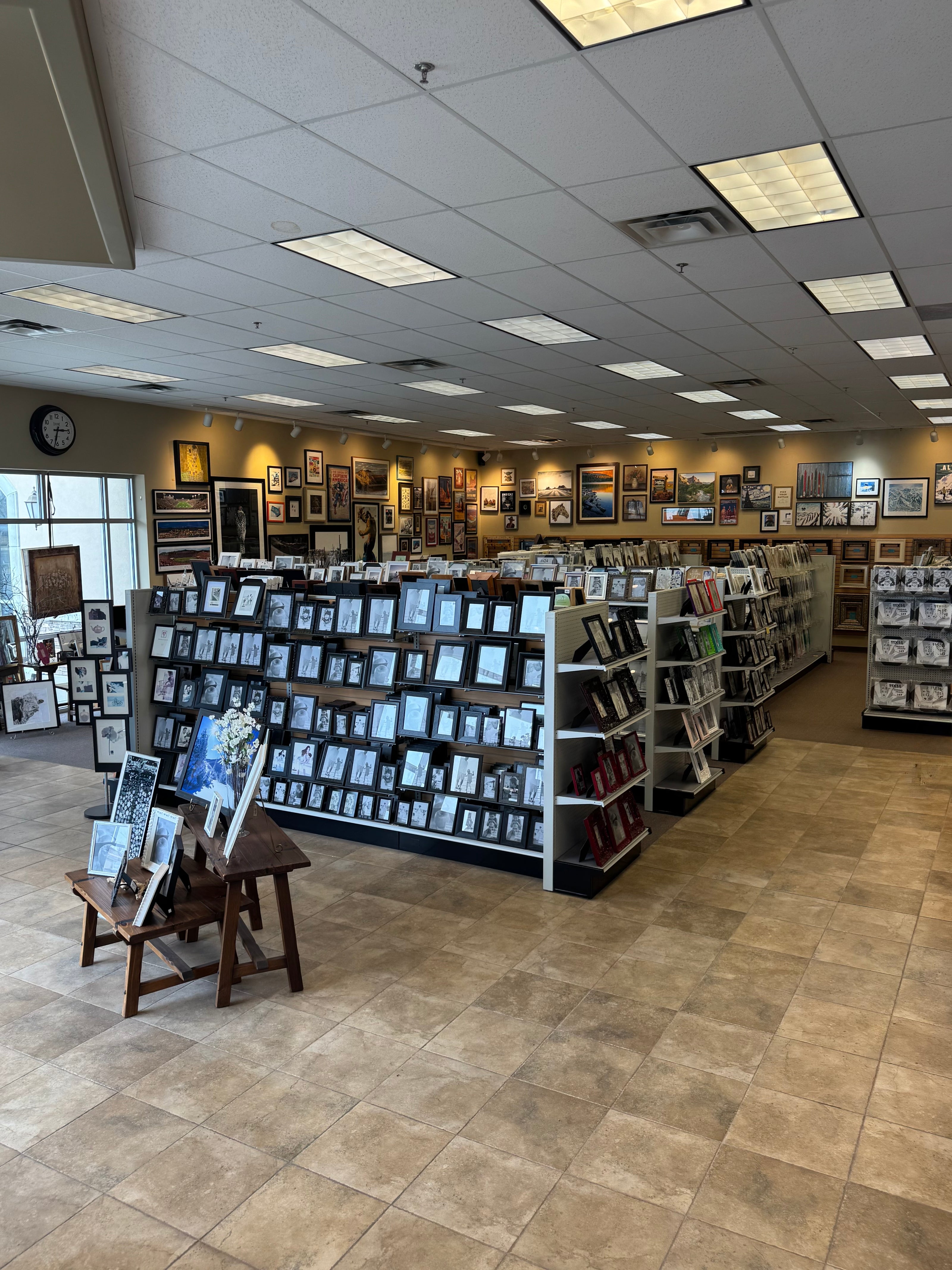 Store interior with shelves displaying picture frames and books on a tiled floor.