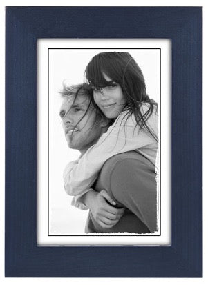 A black and white photo in a blue frame shows a smiling woman with long hair giving a piggyback ride to a man. Both appear content and relaxed.