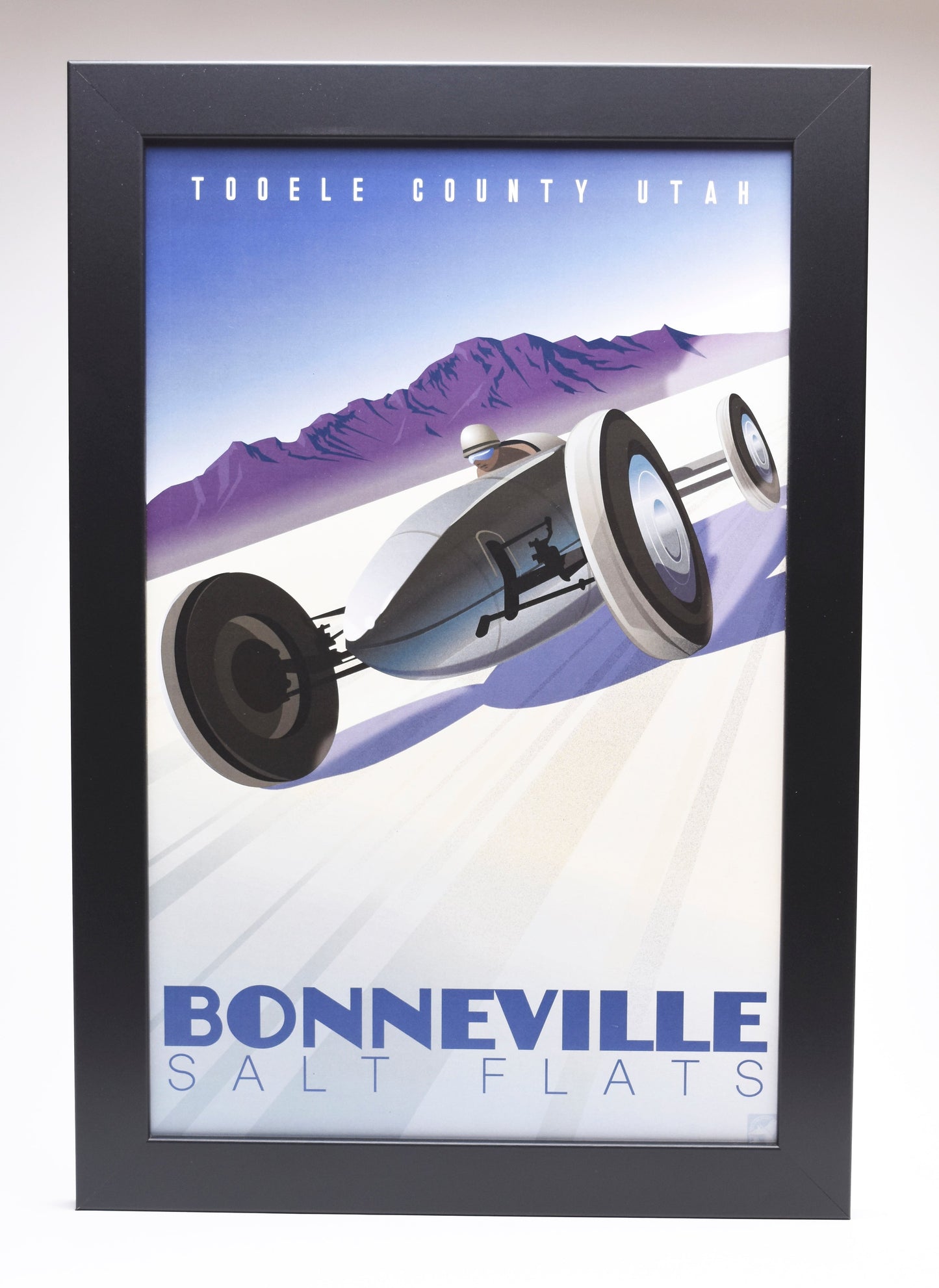Poster of a vintage race car speeding on Bonneville Salt Flats, Utah, against purple mountains and blue sky. Bold text: "Bonneville Salt Flats."