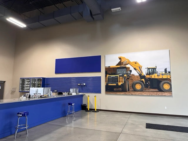 A framed image of a construction vehicle on a large blue wall, creating a striking visual contrast.