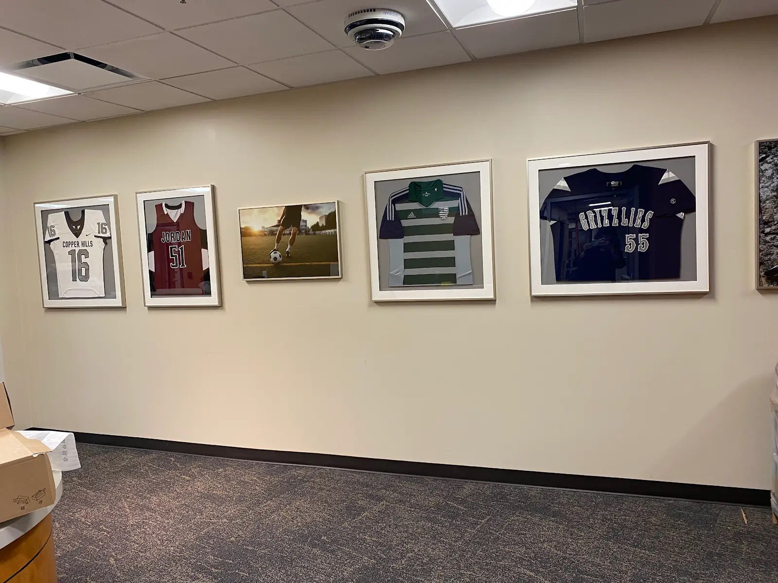 Framed sports jerseys and photos on a wall in an indoor setting