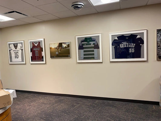 Framed sports jerseys and photos on a wall in an indoor setting