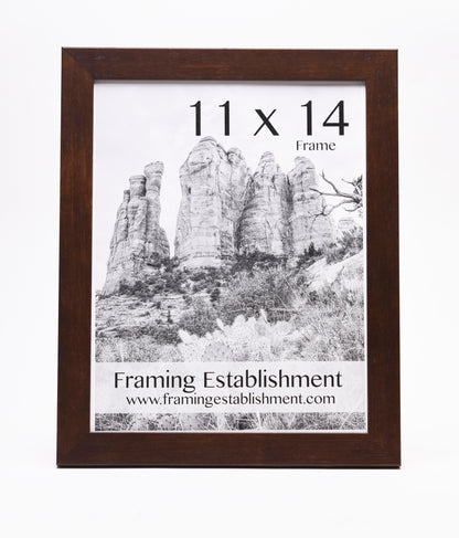 A wooden picture frame holding a black-and-white photo of large rock formations. Text reads "11 x 14 Frame" and "Framing Establishment" with a website link.