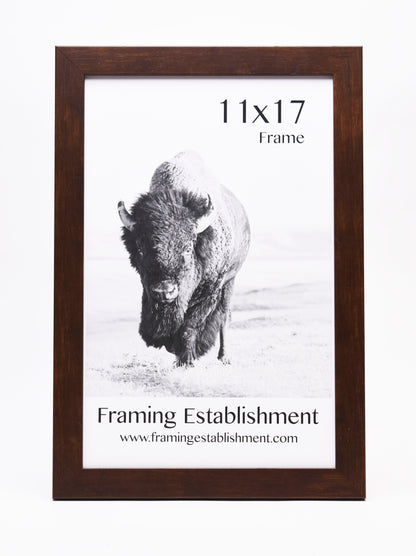 A brown wooden 11x17 frame showcases a monochrome photo of a bison in a snowy landscape. Text below reads "Framing Establishment" with a website link.