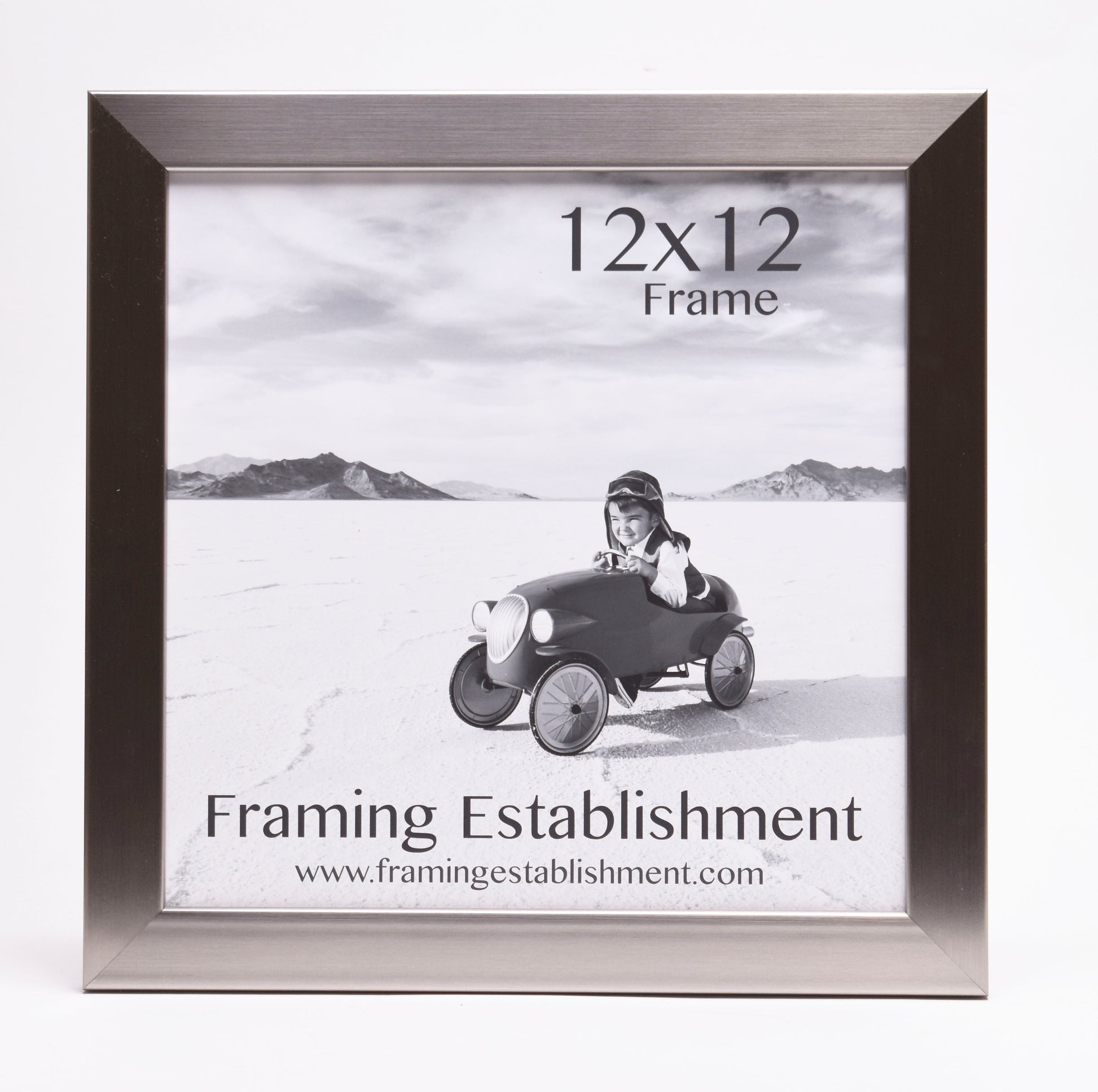 Black and white photo of a child in vintage car, wearing aviator cap, set in a sleek 12x12 frame, suggesting adventure. Text: "Framing Establishment."