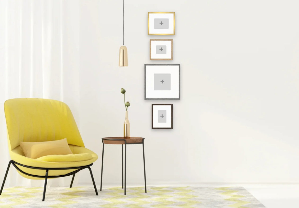 Yellow chair in a room with a white wall, side table, and framed pictures.