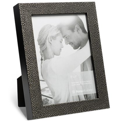 A textured dark grey picture frame holds a black-and-white photo of a couple gently embracing, conveying warmth and affection. The frame stands upright.