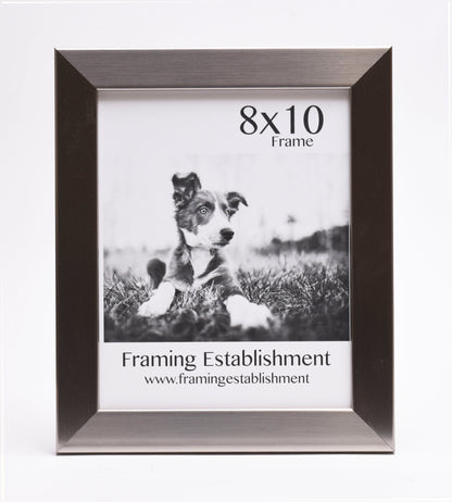 A black and white photo frame holds a picture of a puppy lying on grass. The top reads "8x10 Frame," and the bottom says "Framing Establishment."