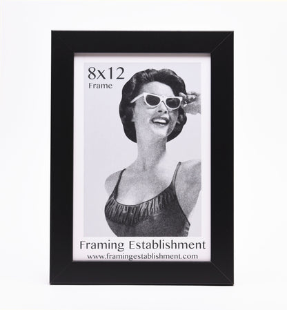 Black picture frame showcasing an 8x12 vintage-style image of a smiling woman in sunglasses and a swimsuit. Text reads "Framing Establishment."