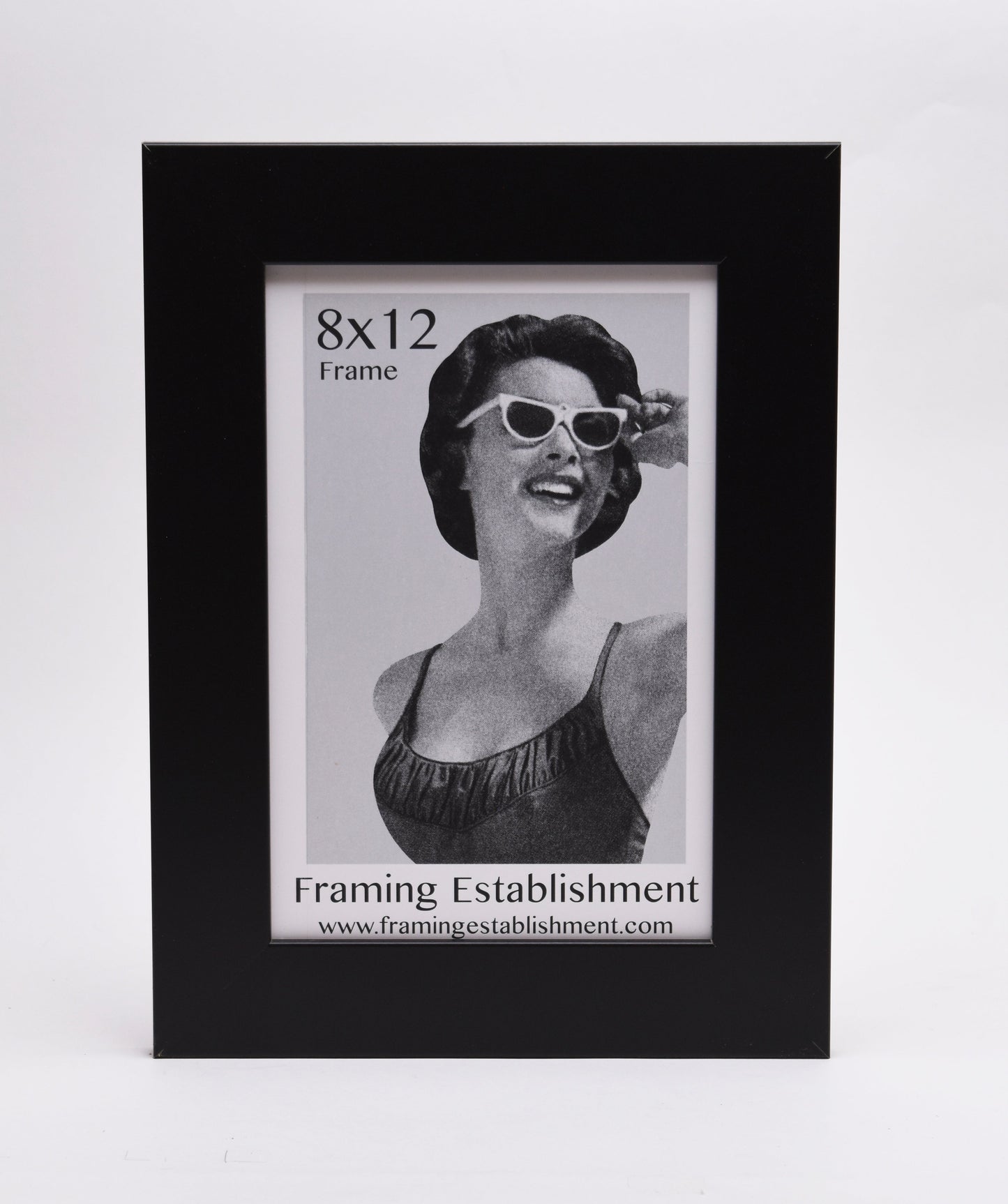 A black frame displays a vintage-style black-and-white photo of a smiling woman in sunglasses. Text reads "8x12 Frame" and "Framing Establishment."