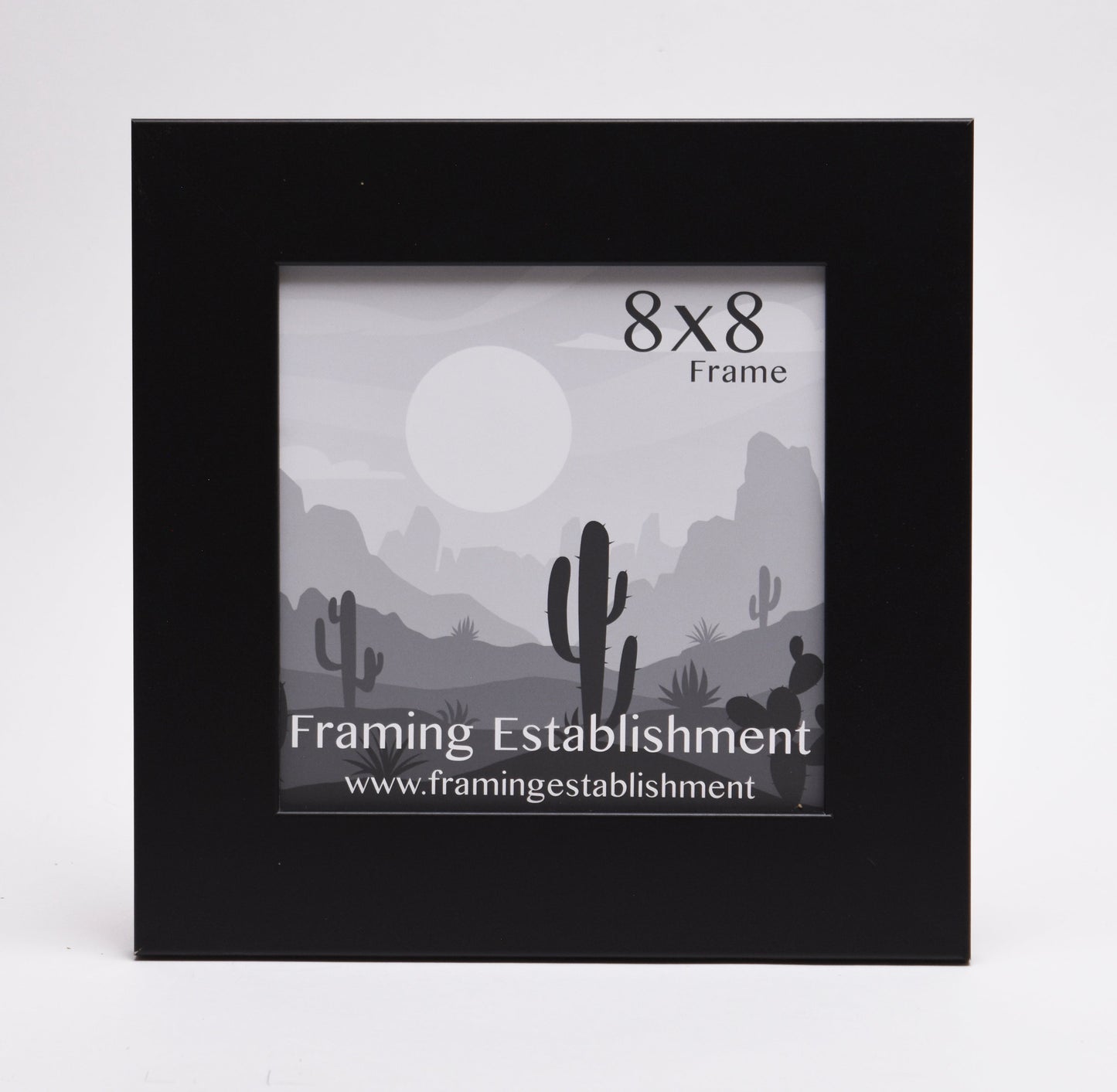A black 8x8 photo frame with a minimalist desert landscape illustration inside. The image features cacti, hills, and a large sun. A calm, serene tone.