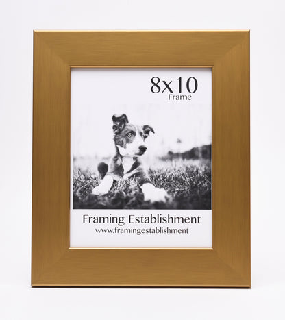 A golden 8x10 photo frame showcasing a black and white image of a playful puppy on grass. Below, it reads "Framing Establishment" with a website link.