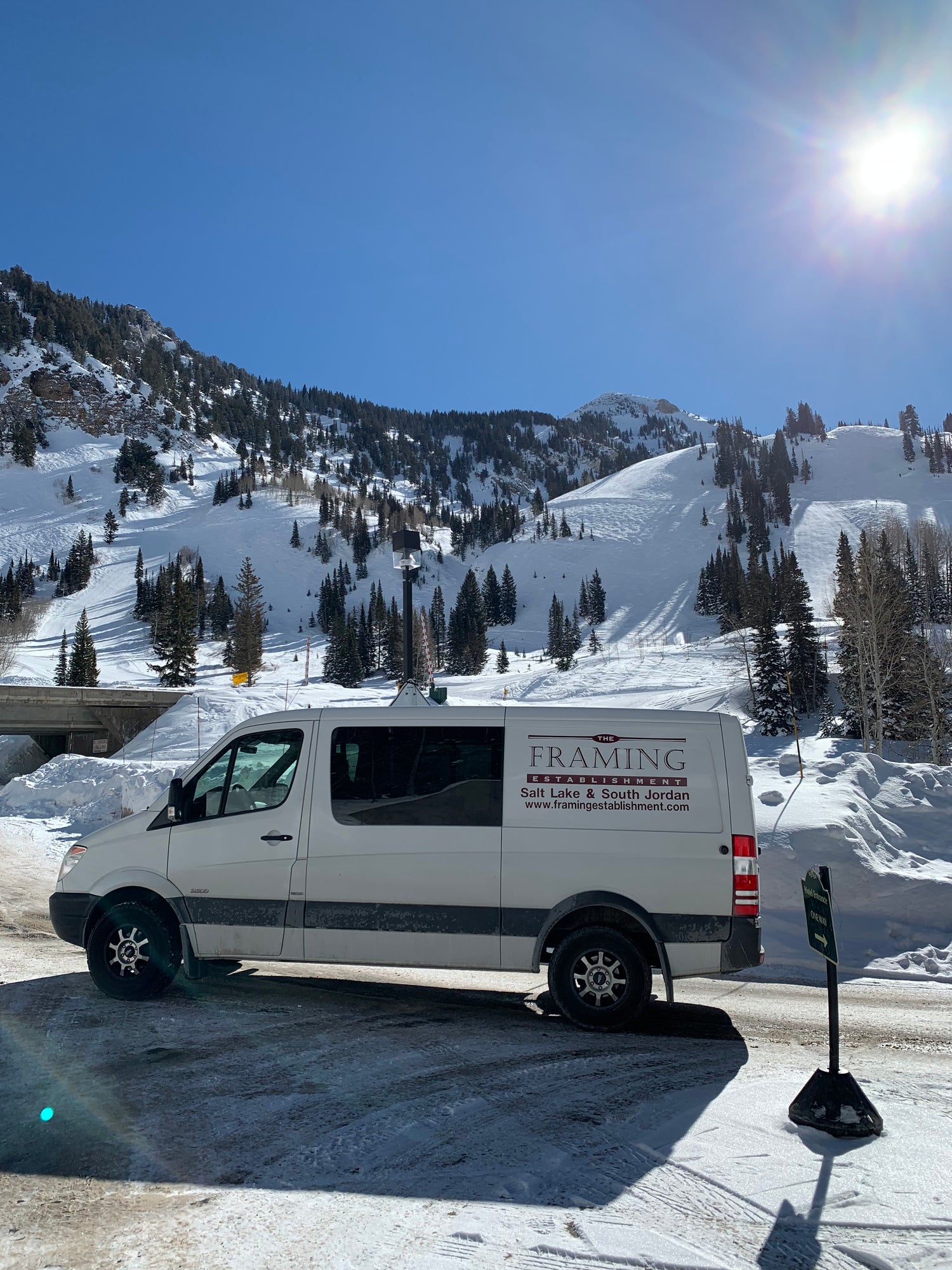 Van parked on a snowy road with mountains in the background